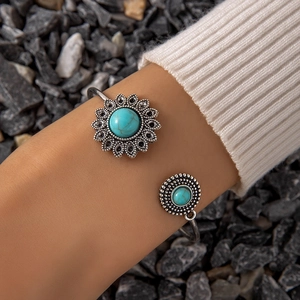 Bohemian silver bangle with turquoise stone inlay on a model's wrist against stones