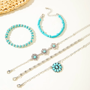 Macro detail of 5-piece bohemian turquoise jewelry set with sunburst and floral charms