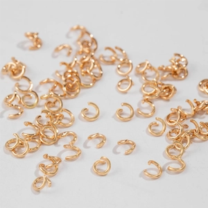 DIY jewelry making supplies featuring bulk gold open jump rings on a neutral background