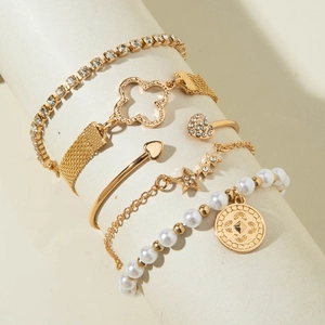 Détail d'un ensemble de 5 bracelets dorés avec breloques cœur, étoile et perles de mode