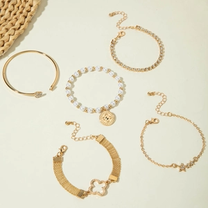 Détails d'un ensemble de cinq bracelets dorés avec perles, étoiles et cristaux brillants