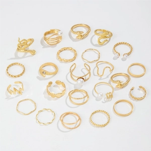 Set of 21 gold snake rings with imitation pearls and rhinestones on white background