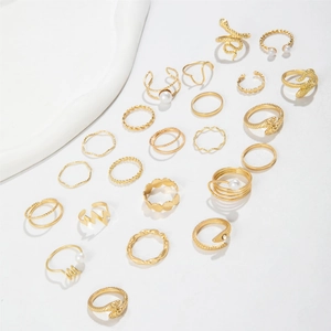 Flat lay of multiple vintage gold snake rings and minimalist pearl accent rings set