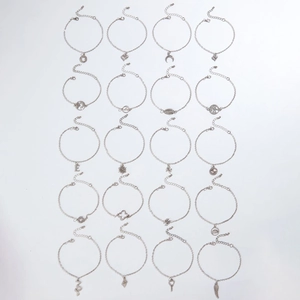 Set of 20 silver-tone anklets with heart, moon, and tree of life pendants in a flat lay view