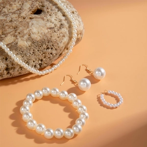 Elegant white faux pearl jewelry set with necklace, bracelet, earrings and ring on stone