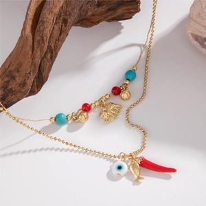 Close-up of bohemian layered gold necklace with chili, evil eye and elephant charms