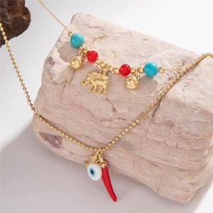 Detail of beaded necklace with gold elephant, devil's eye and red chili pendants