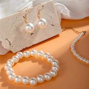 Elegant pearl jewelry set with necklace, bracelet, and earrings on stone background