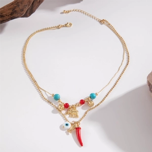 Macro detail of bohemian layered gold necklace with evil eye and chili charms