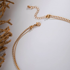 Detailed view of golden double-layer chain necklace with lobster clasp and extension