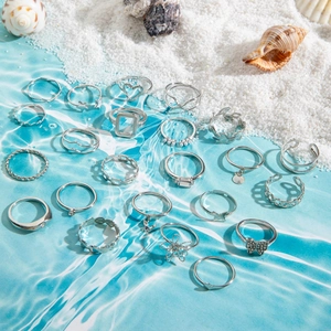 Set di anelli vintage argentati con cuori e stelle su sfondo a tema spiaggia estiva