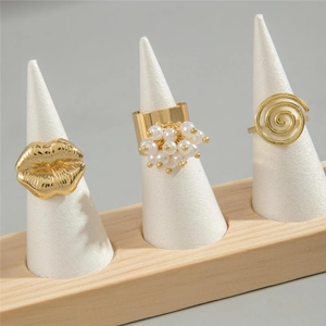 Three-piece gold lip and pearl ring set with spiral design on minimalist cone display