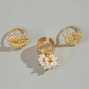 Three-piece gold lip and pearl ring set featuring spiral texture on grey background