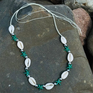 Detail of beach body chain featuring natural white shells and cyan starfish beads