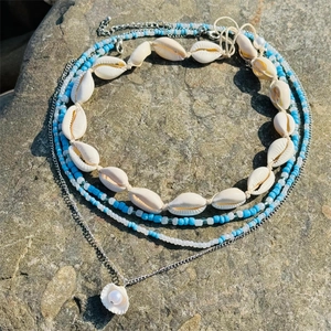 Ensemble de colliers bohèmes en coquillages et perles bleues sur roche pour la plage
