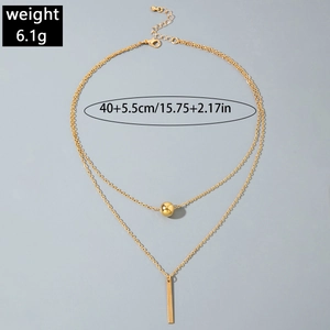 Detail of layered gold Y-necklace featuring bead pendant and vertical bar drop element