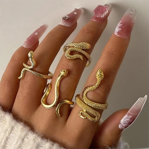 Close-up of a 4-piece set of gold snake rings with scale textures and smooth finishes