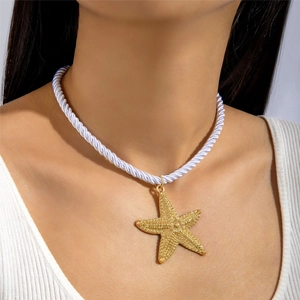 Close-up of golden starfish pendant with textured finish on a white twisted rope chain