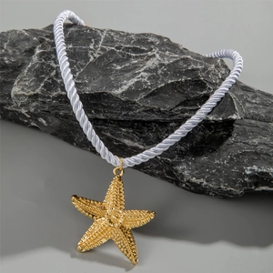 Detailed view of a gold starfish pendant necklace with textured finish on dark stone
