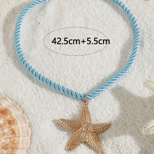 Detail of starfish pendant necklace with light blue twisted cord on white sand beach