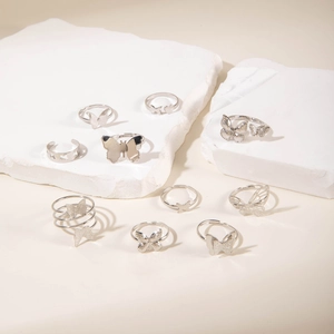 Close-up of 9-piece silver butterfly ring set on white stone props with polished details