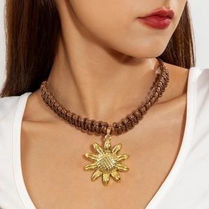 Detail of sunflower pendant on a brown braided cord showing high-quality metallic texture