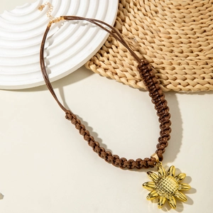 Detailed close-up of golden sunflower pendant with brown woven cord necklace