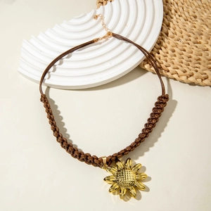 Macro detail of sunflower pendant with golden petals and woven cord on a textured base