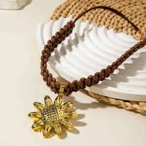 Macro detail of sunflower pendant with golden petals and brown woven cord on stone
