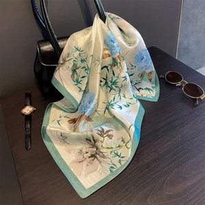 Detailed texture of a 53cm silk scarf with blue floral and green bamboo patterns