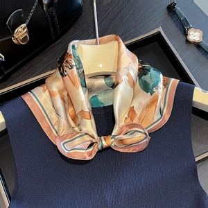 Detailed view of luxury 100% silk floral scarf styled on a navy knit sweater