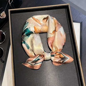 Silk square scarf with abstract floral pattern tied in a bow on a display tray