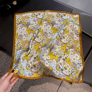Detail of a 53cm silk square scarf with yellow floral patterns and smooth satin texture