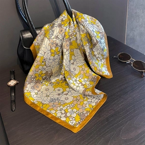 Close-up of a floral silk scarf styled on a luxury handbag with retro accessories
