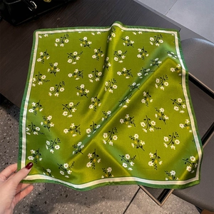 Dettaglio del foulard quadrato in seta verde smeraldo con motivi floreali e finitura satin