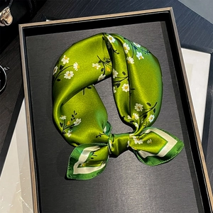 Foulard di seta verde con stampa a margherite annodato a fiocco su vassoio