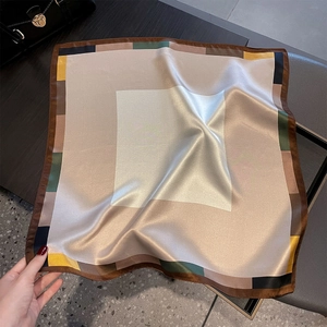 Dettaglio ravvicinato di un foulard in seta con motivo geometrico e bordi cuciti a mano