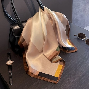 Elegante foulard in seta con stampa geometrica drappeggiato su borsa in pelle nera