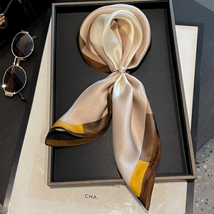 Elegante sciarpa in seta con motivi color block e fibbia in perle su vassoio espositivo