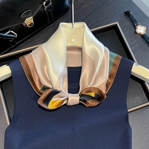 Dettaglio ravvicinato di una sciarpa di seta stampata con un maglione blu a costine