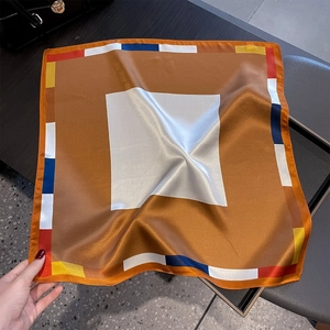 Vista dettagliata di un foulard quadrato in seta con trama satinata e bordi geometrici