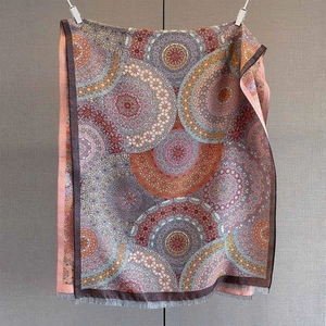 Détail d'une écharpe mandala bohème avec pompons et motifs automnaux multicolores