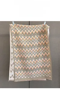 Detail of soft geometric wavy pattern and fine fringe on a thick winter scarf shawl