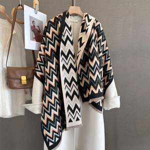 Detail view of thick cashmere scarf featuring orange wavy patterns and fringe edges