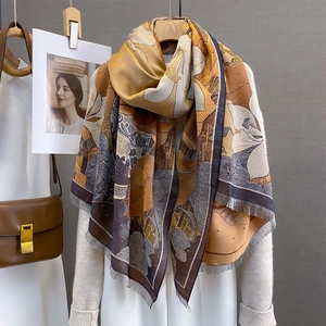Detail of artistic floral scarf with tassels paired with a beige knit cardigan
