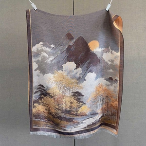 Close-up of woven autumn landscape scarf with golden sunset peaks and tassel edge