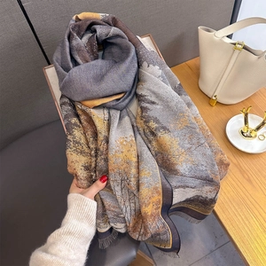 Detail view of autumn forest landscape print and fringe edges on a soft cashmere-feel scarf