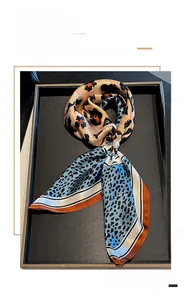Detail of silk square scarf featuring leopard print and blue dotted patterns with pearl buckle