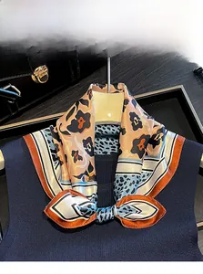 Detail of 100% Mulberry silk scarf with leopard and floral patterns on a navy sweater