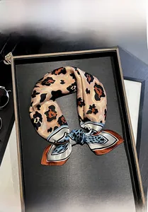 Detail of 100% mulberry silk scarf featuring leopard print on a display tray